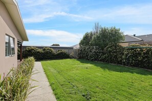 Enjoy a serene outdoor space with a well-manicured lawn and lush plants.