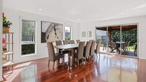 Un comedor amplio con una mesa grande y sillas, ventanas grandes y vistas al exterior.