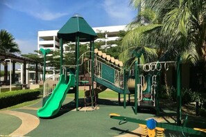 Kids can play on the green slide, climbing structure, and seesaw in this landscaped playground area.