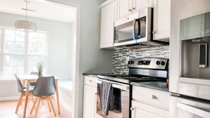 Une cuisine moderne avec des meubles blancs, un four en acier inoxydable et un four à micro-ondes.