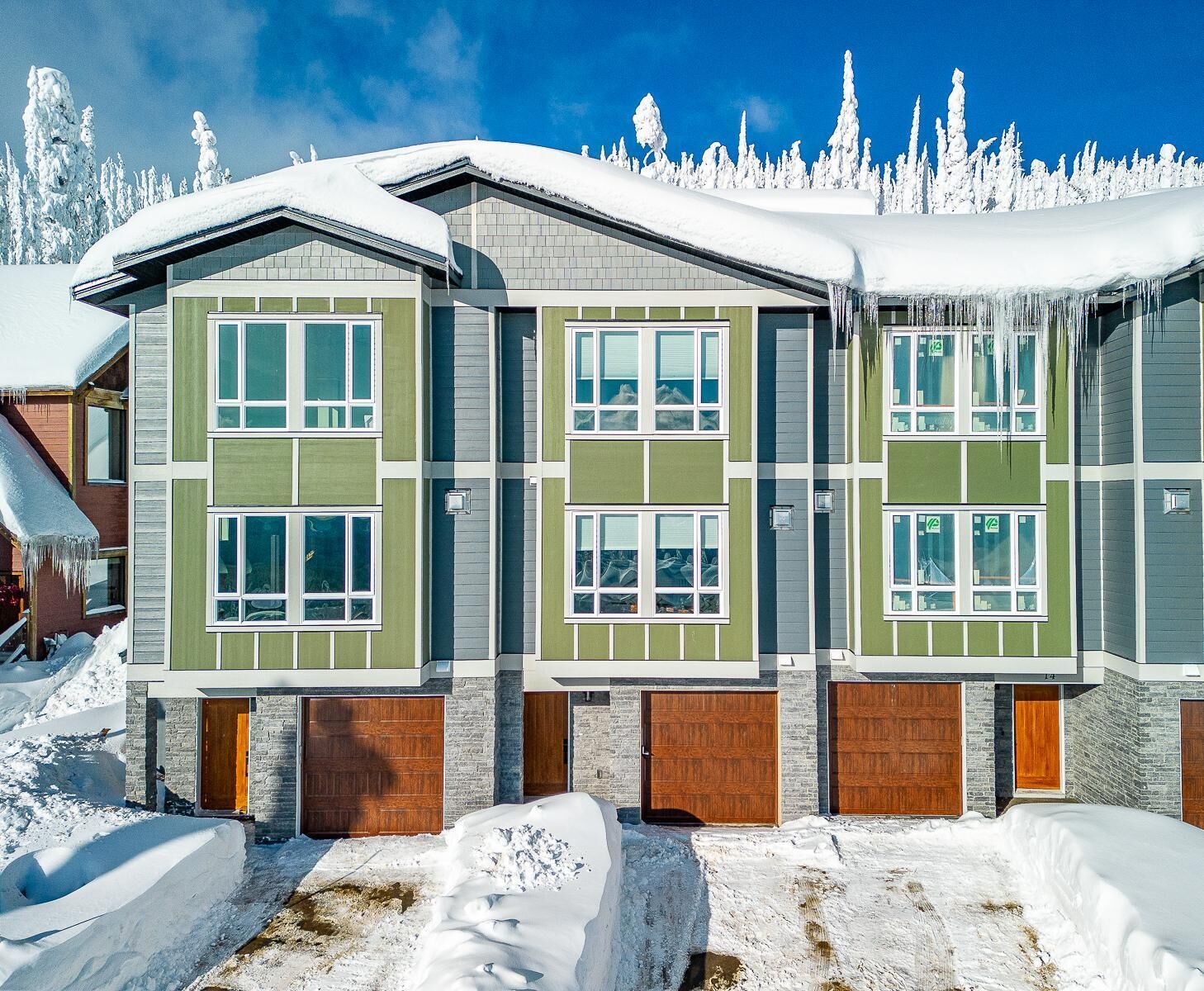 Un edificio de varios pisos con fachada simétrica, ventanas amplias y techo cubierto de nieve.