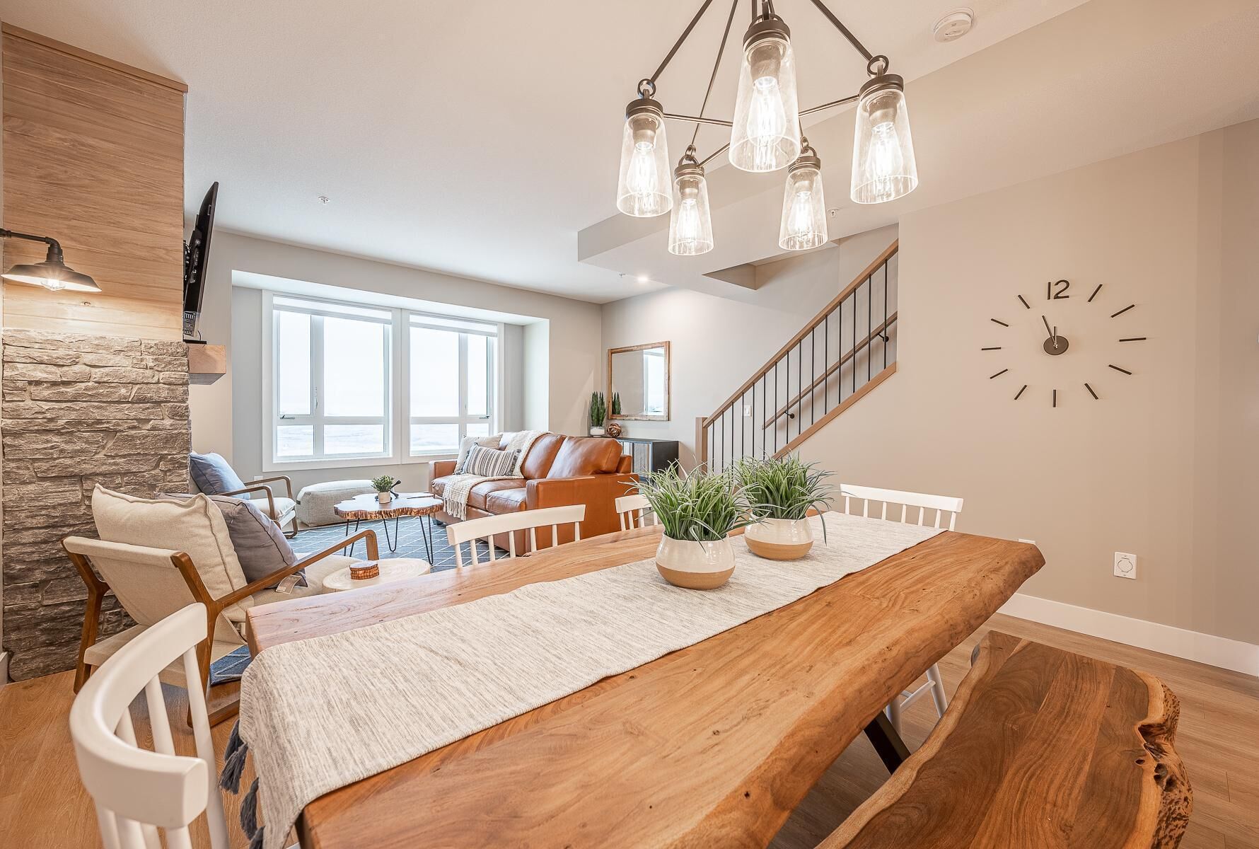 Un salon spacieux avec une table à manger en bois, des sièges confortables et un escalier menant à un autre niveau.