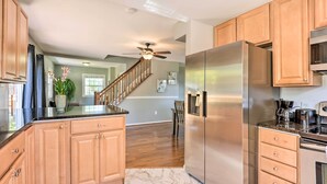 Una cucina moderna con mobili in legno, un frigorifero in acciaio inossidabile e una ventola a soffitto.
