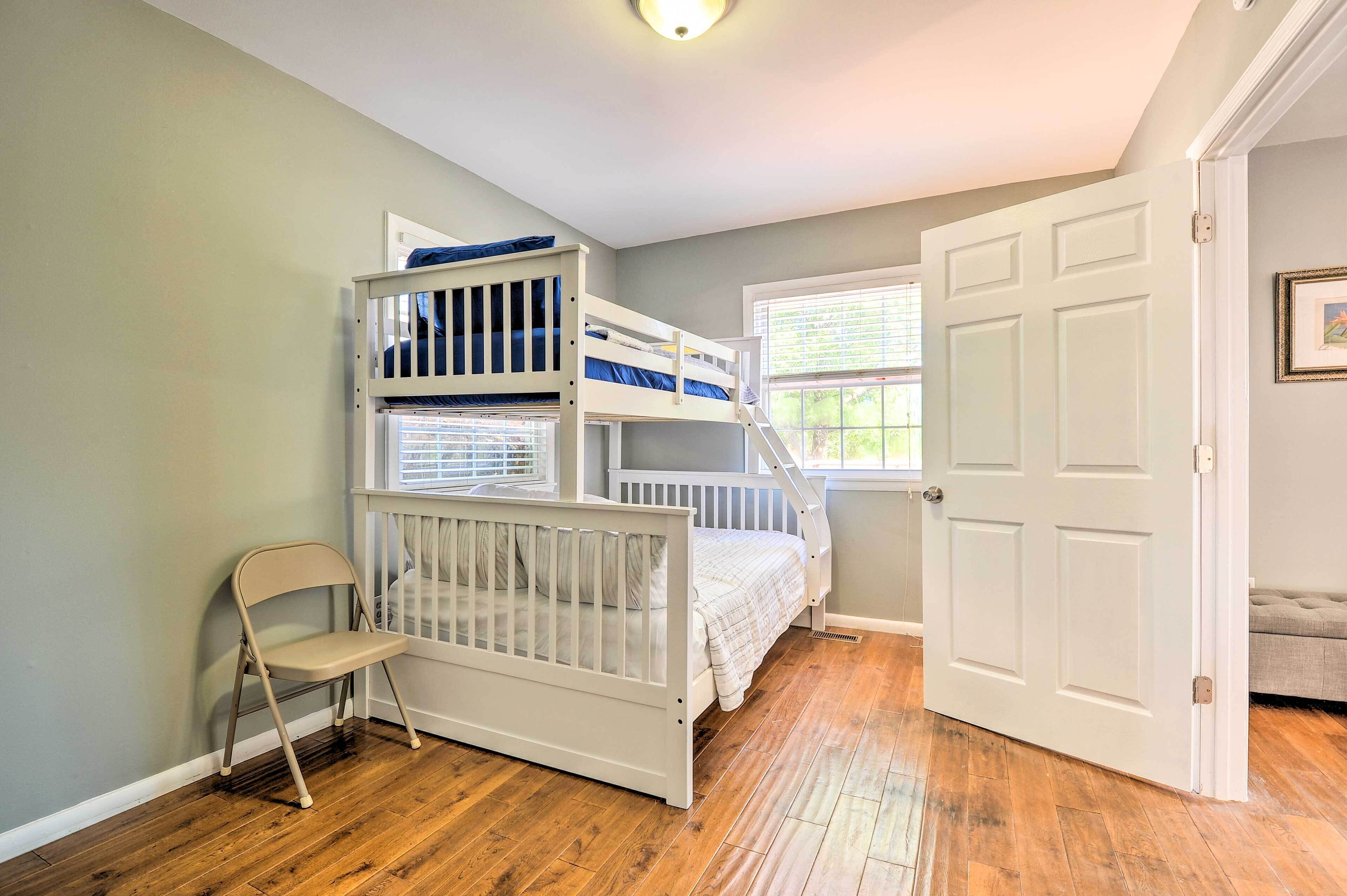 A room with a bunk bed, a small chair, and a door.