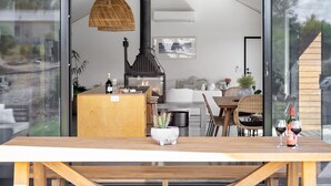 Et moderne opholdsrum med et træbord, en pejs og en glasdør, der fører til et udendørs område.