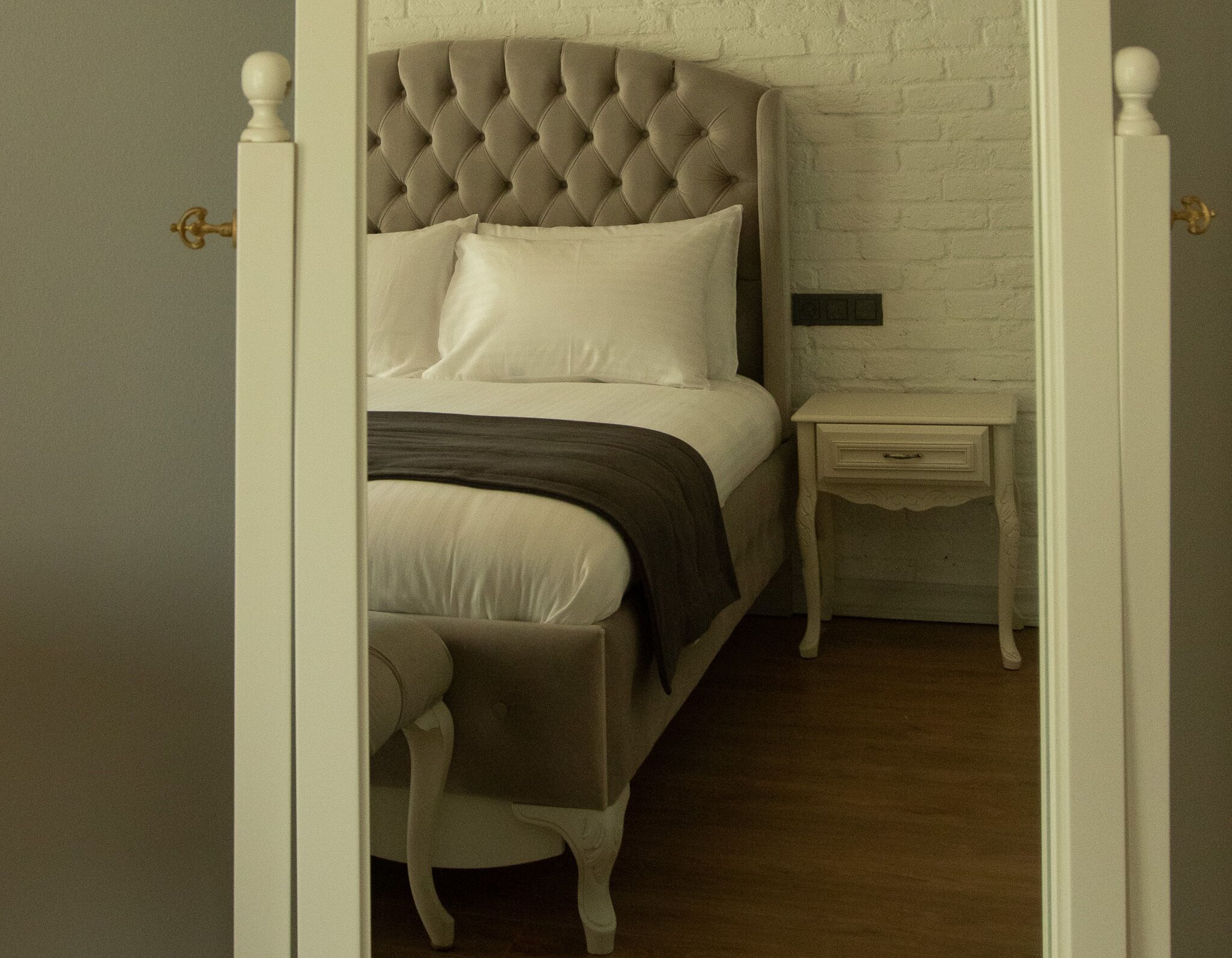 Une chambre à coucher avec une tête de lit capitonnée, une table de chevet et une commode.