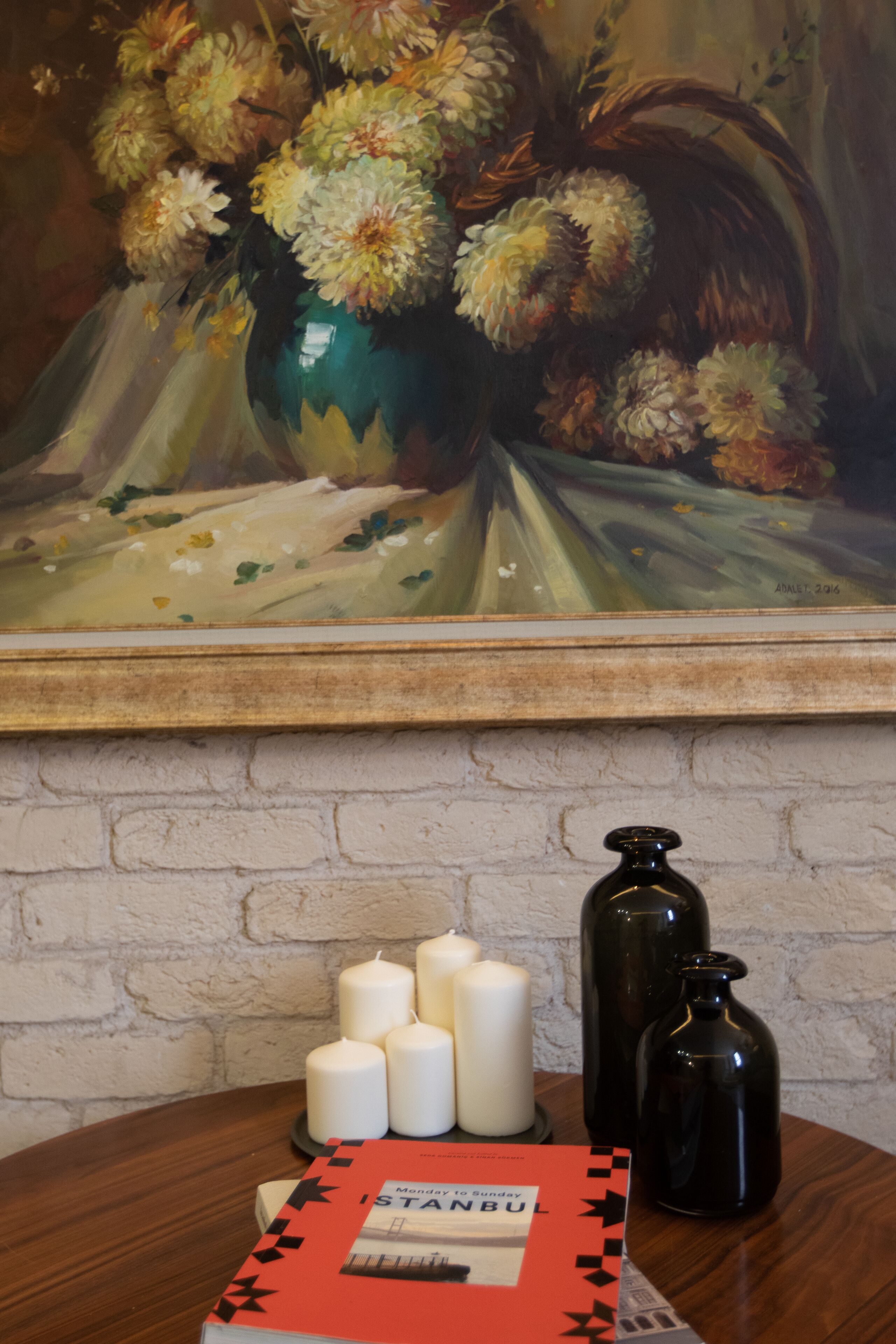 A table with candles, a book titled "ISTANBUL," and a vase with flowers.
