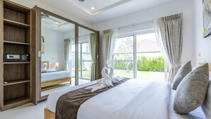 A bedroom with a large bed, a wooden wardrobe, a mirror, and a view of the outdoors. - Private 3 Bedroom Pool Villa MS22 (Hua Hin)