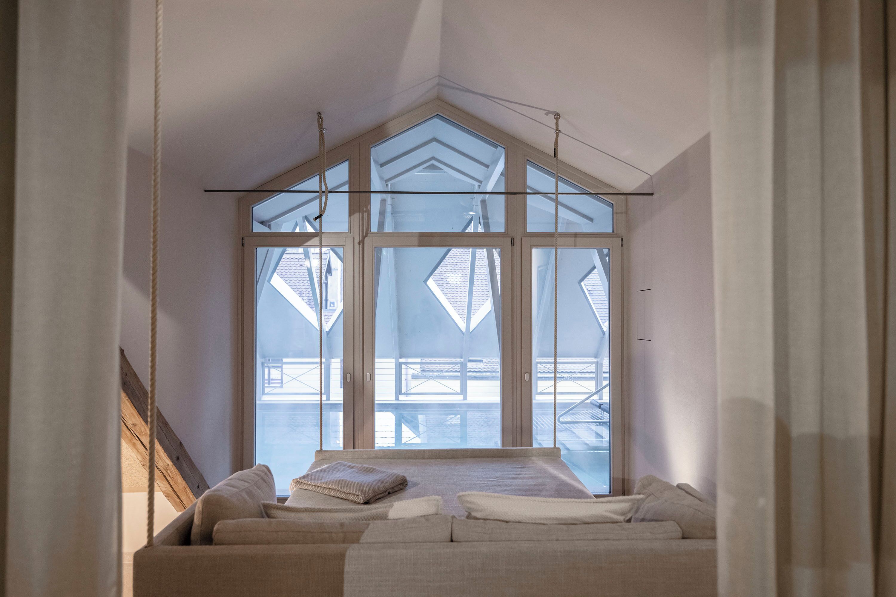 A bedroom with a large skylight, a bed with pillows, and a view of the outside.