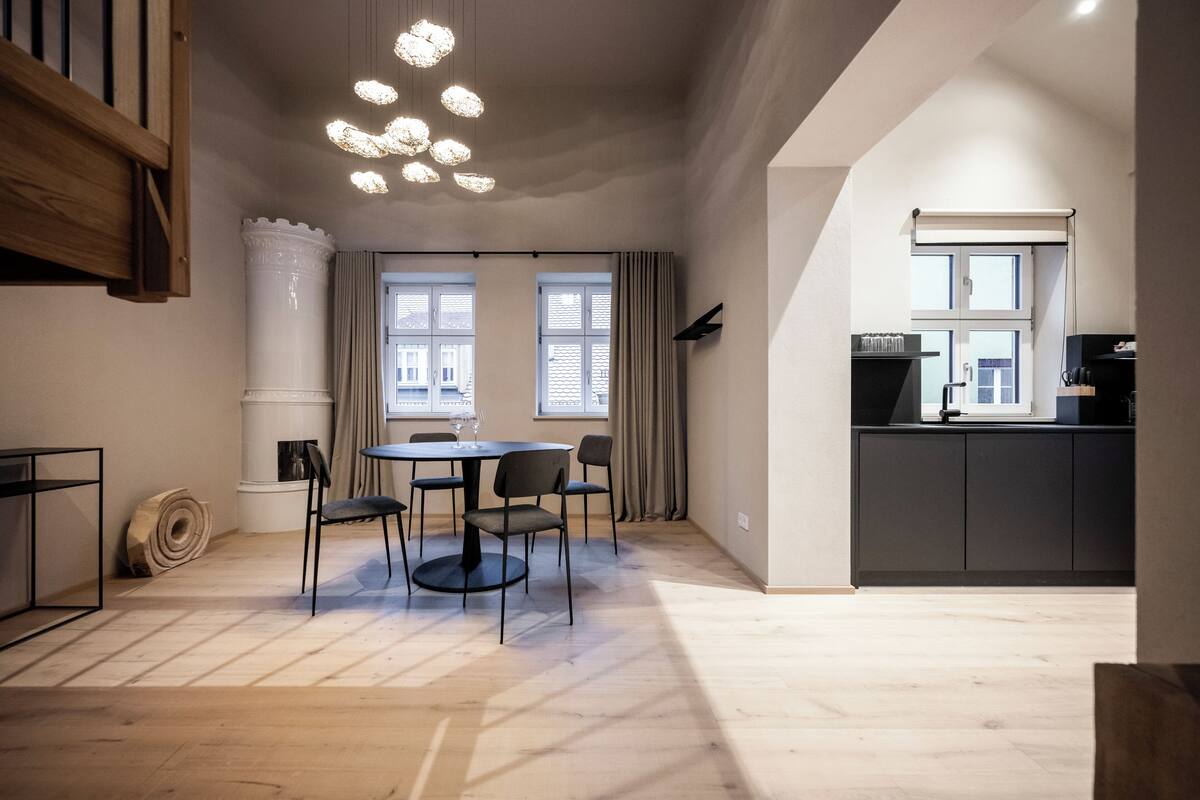 Eine moderne Küche mit Essbereich, Holzboden und einem großen Fenster, das für natürliches Licht sorgt.