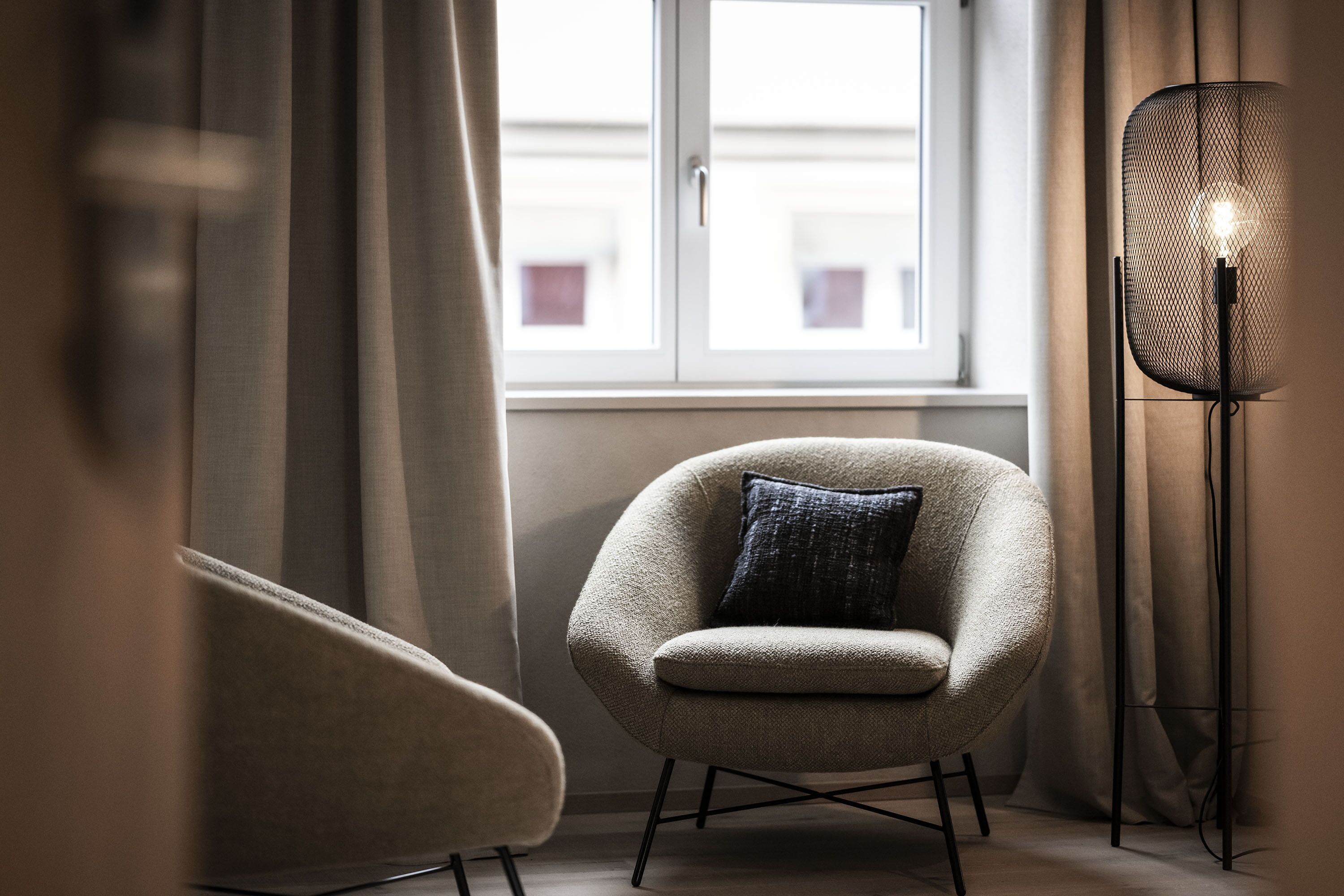 Une pièce avec une fenêtre, une chaise et un lampadaire.