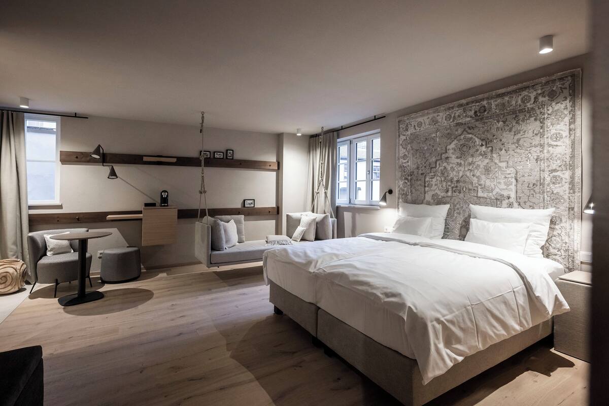 Ein modernes Schlafzimmer mit einem großen Bett, einer Couch, einem kleinen Tisch und einem großen Teppich.