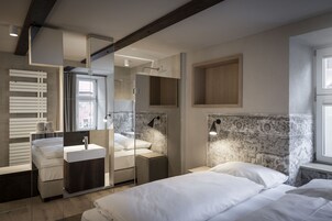 Un dormitorio moderno con cama, mesitas de noche, un espejo y una ventana.