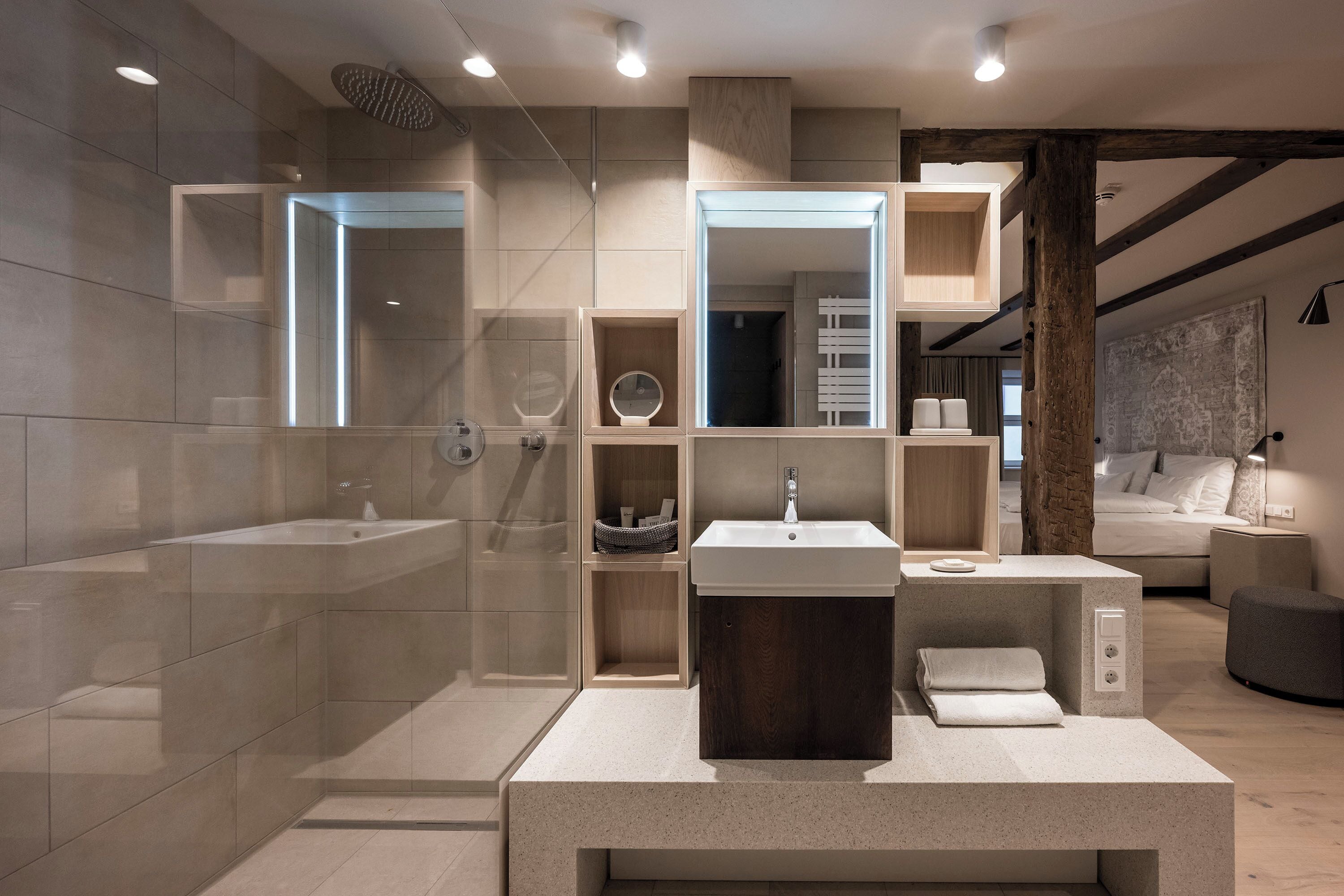 Un baño moderno con una bañera grande, un lavamanos y una zona de ducha. Hay un espejo sobre el lavamanos y un perchero a su lado.