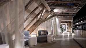 Et moderne interiør med loft til kip, et siddeområde med sofa og skærmpude, samt et køkkenområde med bordplade og skabe.