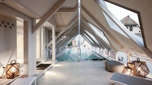 Un interior moderno con una escalera de cristal, una zona de estar y vistas a un edificio histórico.