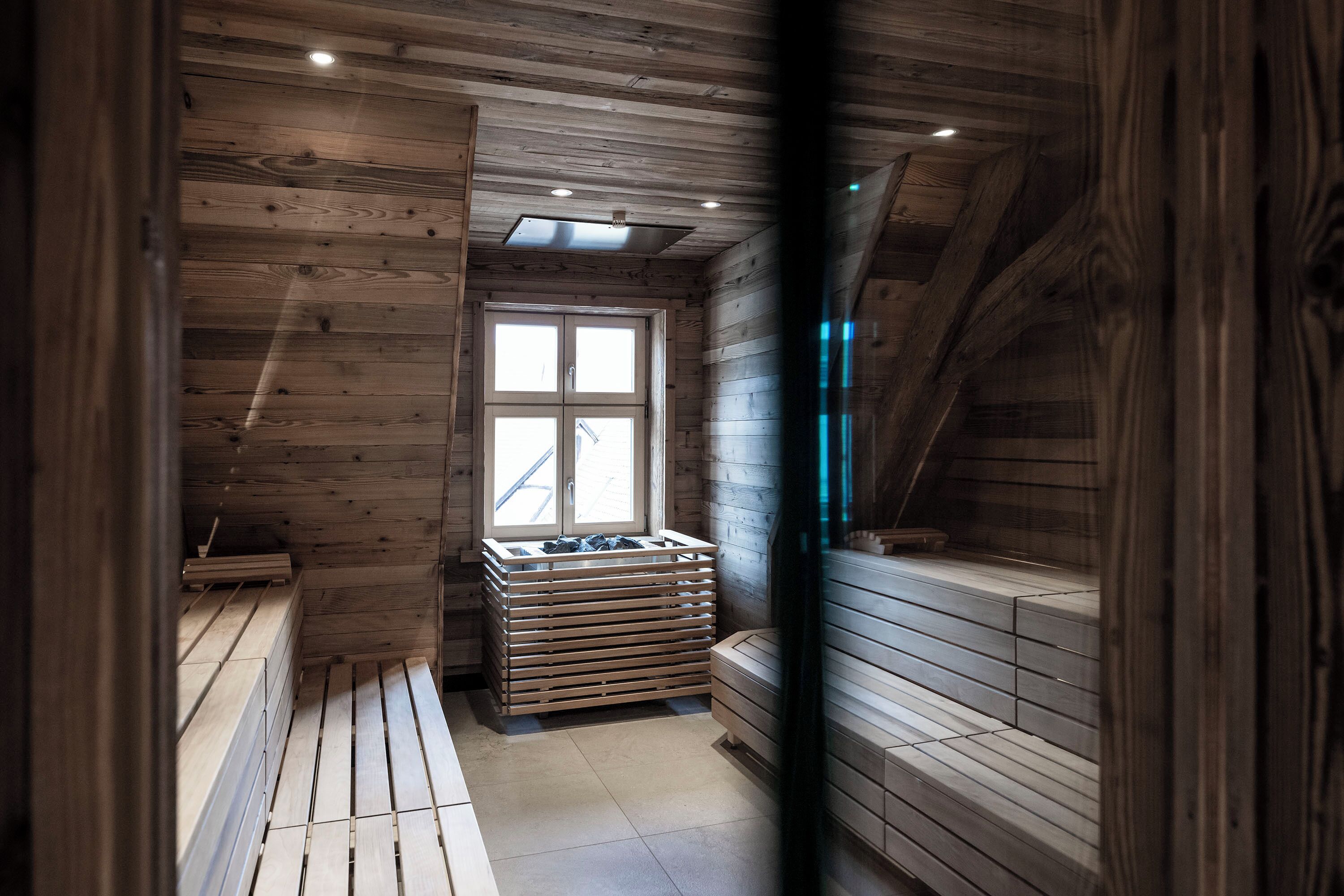 A wooden cabin with a sauna, a window, and a wooden bench.