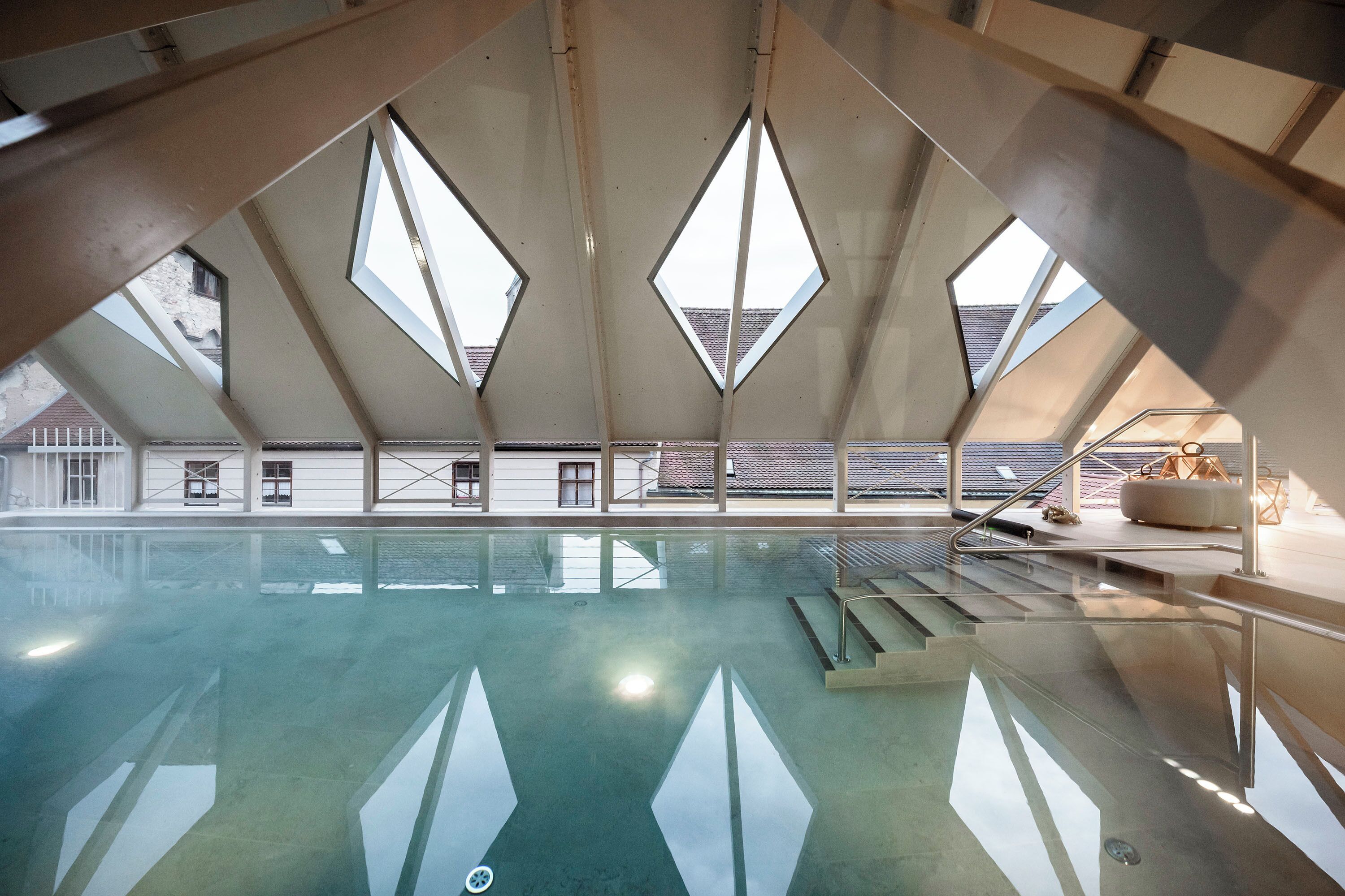 A swimming pool with a clear view of the outside through triangular windows.