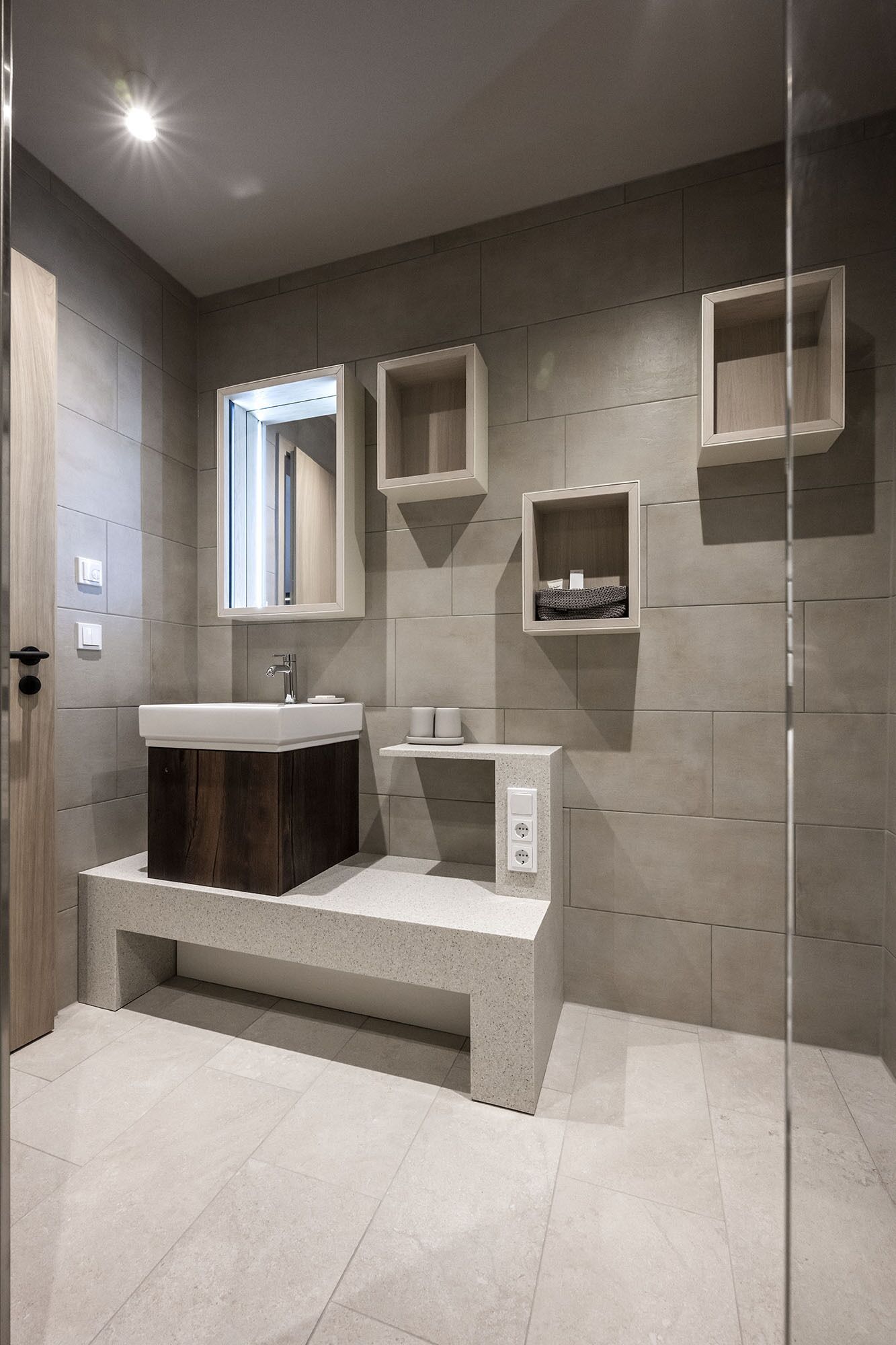 Ein modernes Badezimmer mit einem großen Waschbecken, einem Spiegel und eingebauten Regalen.