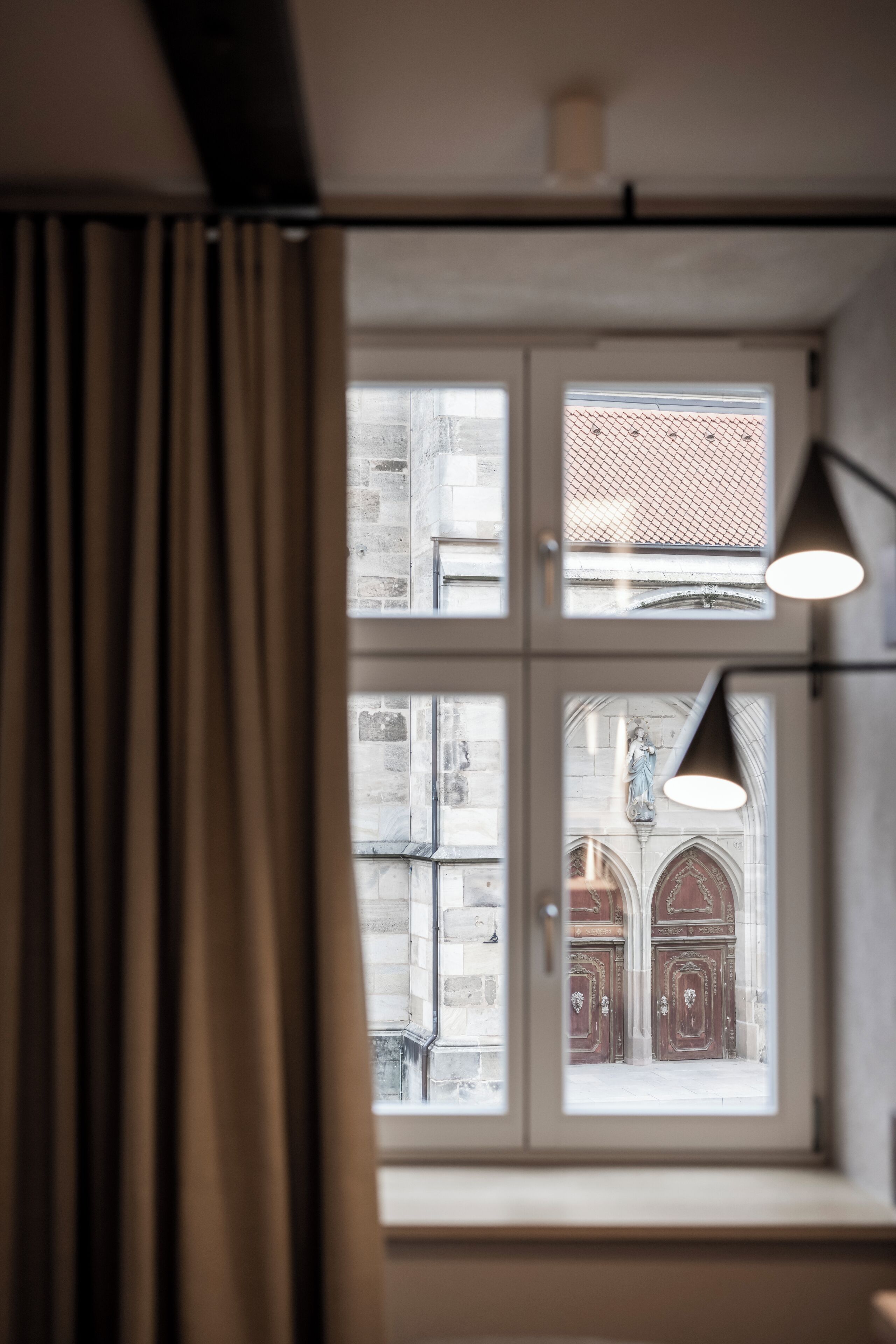 Una habitación con un gran ventanal, cortinas y una lámpara colgante.