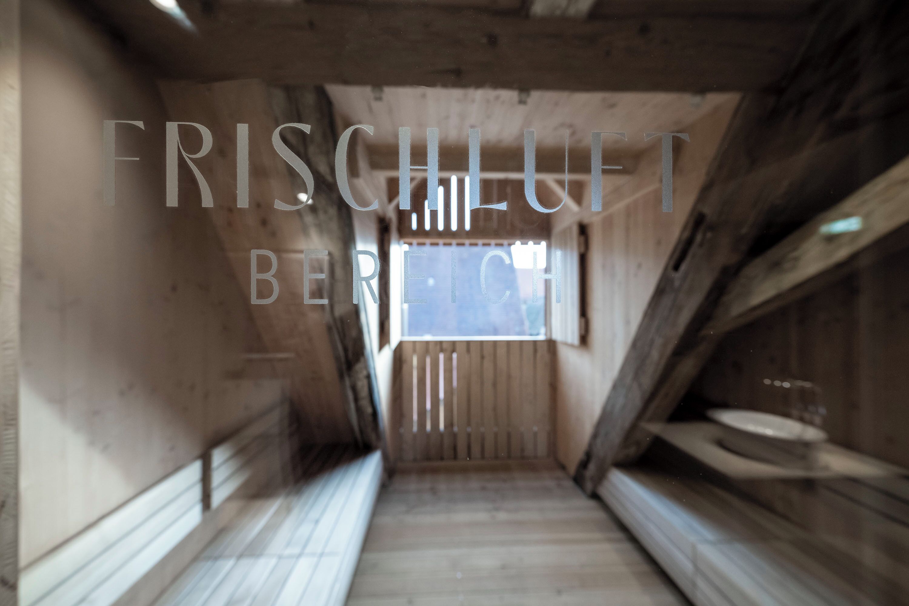 Un couloir étroit aux murs en bois, avec une fenêtre au fond.