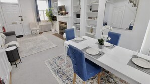 Un salon moderne avec un coin repas, des murs blancs et une cheminée.