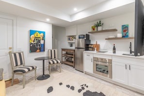 Una cocina moderna con armarios blancos, electrodomésticos de acero inoxidable y un comedor con sillas a rayas.