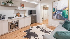 A modern kitchen with white cabinets, a built-in oven, and a flat-screen TV.
