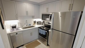A modern kitchen with white cabinets, stainless steel appliances, a dishwasher, and a microwave. - Downtown DC Awaits with Parking Permit (Washington)