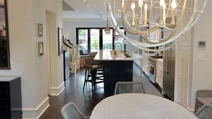 A modern kitchen with a central island, dark flooring, and a unique chandelier. - Luxurious Mansion in Logan Circle Private Parking (Washington)