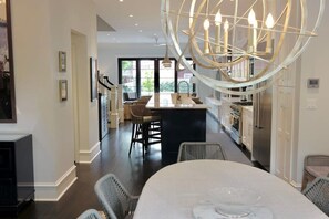 A modern kitchen with a central island, dark flooring, and a unique chandelier.