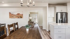 A modern kitchen with white cabinets, a stainless steel refrigerator, and a wooden dining table with chairs. - Rustico Roost by RedAwning (Washington)