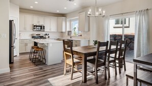 A modern kitchen with white cabinets, a central island, and a dining area with wooden chairs. - Rustico Roost by RedAwning (Washington)