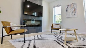 Ein modernes Wohnzimmer mit Kamin, zwei Ledersesseln, einem runden Couchtisch und abstrakter Wandkunst.