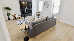 Ein modernes Wohnzimmer mit einem grauen Sofa, einem runden Couchtisch und einem Kamin.