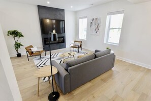 A modern living room with a grey sofa, a coffee table, a TV, and a fireplace.