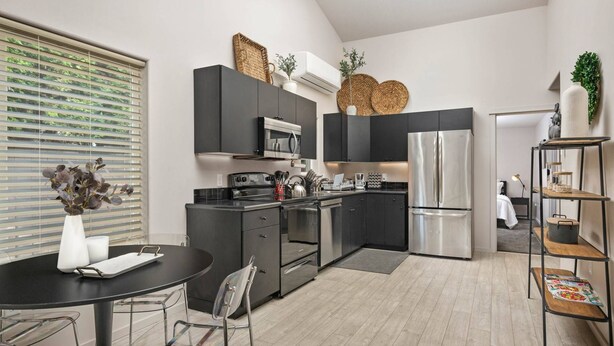 A modern kitchen with dark cabinetry, stainless steel appliances, and a round dining table with metal chairs. - Prime Location, Pet Friendly, Single Level, New Decor and Furnishing, 10 Min to PDX and Vancouver (Vancouver)