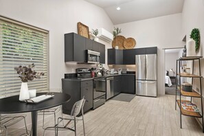 A modern kitchen with dark cabinetry, stainless steel appliances, and a round dining table with metal chairs. - Prime Location, Pet Friendly, Single Level, New Decor and Furnishing, 10 Min to PDX and Vancouver (Vancouver)