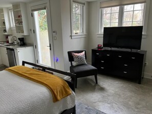 Ein Schlafzimmer mit Bett, Fernseher, Sessel, Kommode und Fenster.