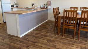 Een moderne keuken met een centraal eiland, een houten eettafel en stoelen.