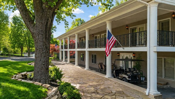 Ein zweistöckiges Gebäude mit überdachter Veranda, einem Kiesweg und einer amerikanischen Flagge.