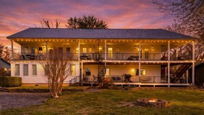 A two-story building with a covered porch, outdoor seating, and a fire pit.