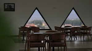 A dining area with triangular windows, wooden chairs, and a tiled floor. - ŞAHİN TERMAL OTEL VE SPA (Kutahya)
