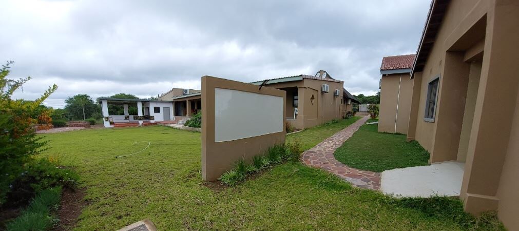 Un quartier résidentiel avec une pelouse verdoyante, un chemin et un bâtiment à la façade beige.