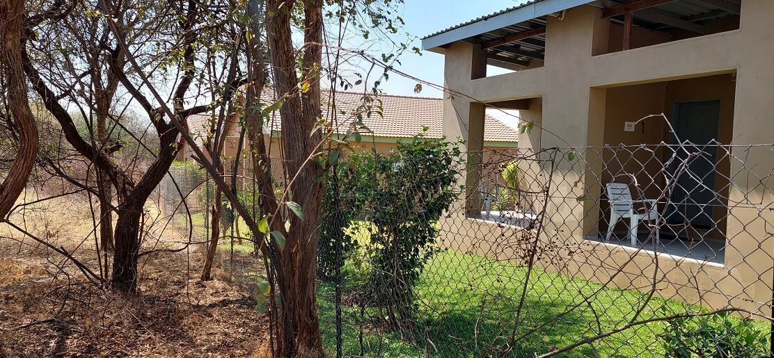 Un espacio al aire libre rodeado por una cerca, con un edificio al fondo.