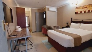 Una habitació d'hotel amb llit, escriptori, cadira, televisió i un quadre a la paret.