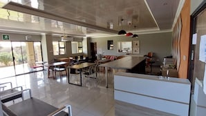 Un vestíbul d'hotel ampli i ben il·luminat, amb una gran recepció, diverses zones d'assaient i grans finestres que deixen entrar llum natural.