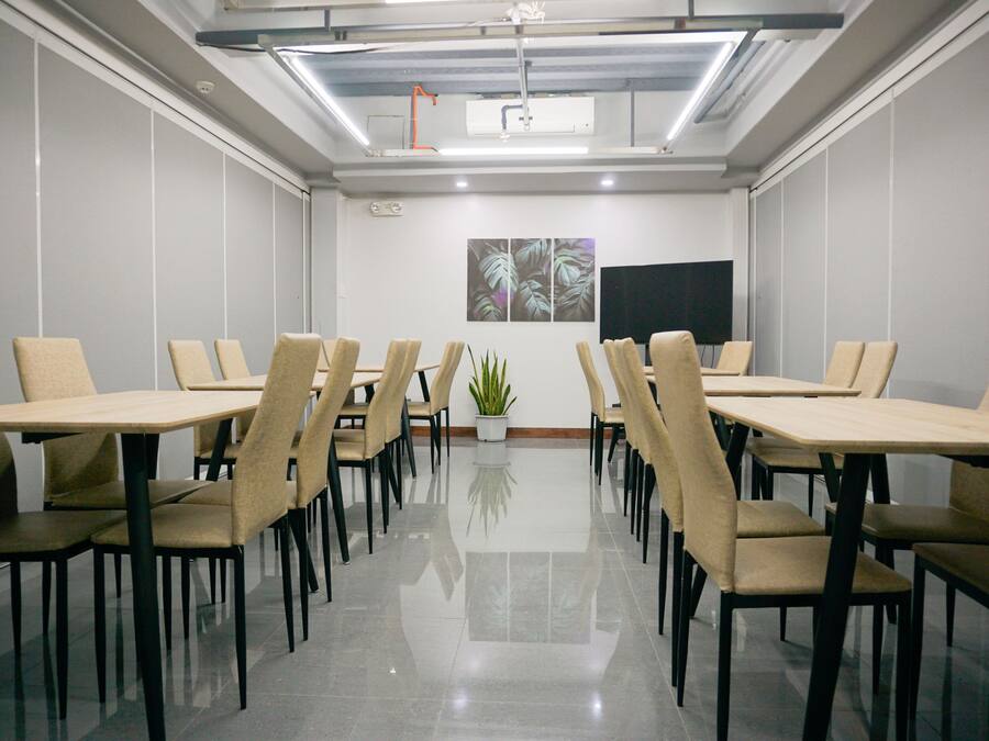 Un salón de conferencias con una mesa larga, varias sillas, una planta en maceta y un televisor de pantalla plana en la pared.