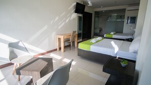 A modern hotel room with a bed, a desk, a chair, and a small table with a plant. - Benrose Hotel (Cagayan de Oro)