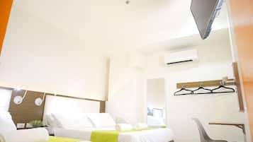 A hotel room with two beds, a desk, a chair, an air conditioning unit, and a television.